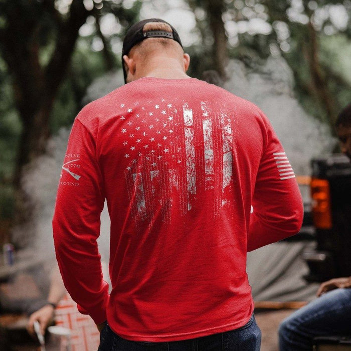 Person wearing a red long-sleeve shirt with a graphic design, standing outdoors.