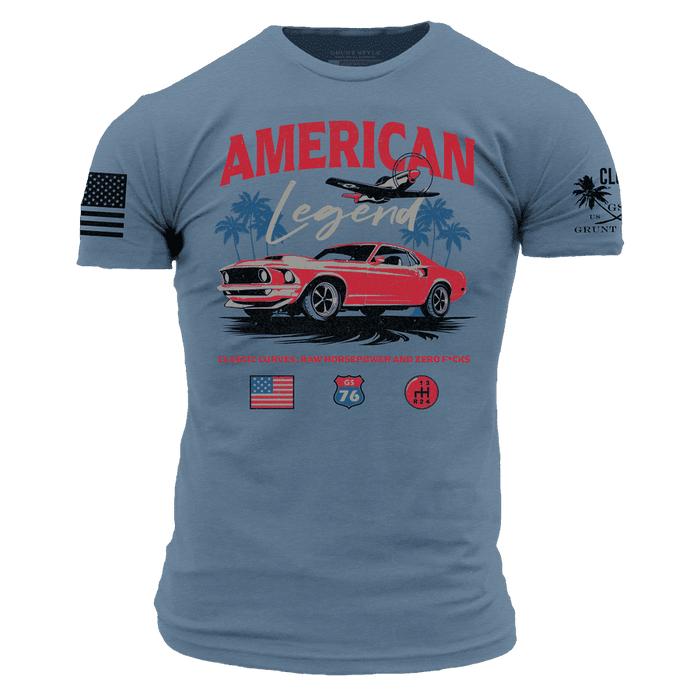A blue short-sleeve graphic t-shirt featuring a red classic Mustang car, the words 'AMERICAN Legend' in red and white, a palm tree and airplane, and additional graphics on both sleeves.