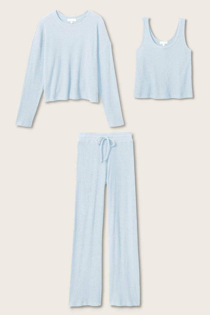 The P.J. Salvage 3-Piece Luxe Ribbed Celestial PJ Set in light blue is displayed flat on a beige background, featuring a long-sleeve top, sleeveless tank top, and drawstring pants.