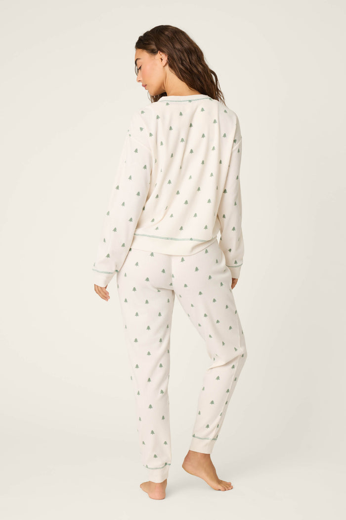 A person stands barefoot on a light background, wearing the P.J. Salvage 4-Piece Tree Print Thermal Lounge Set. With loose hair and a relaxed pose, this cozy set is perfect for cabin getaways or lazy mornings at home.