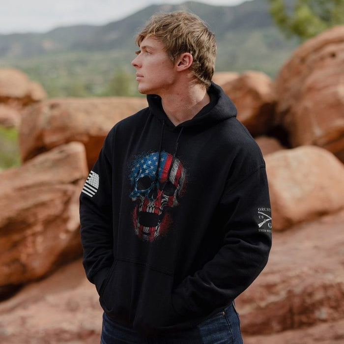 Person wearing a black hoodie with a skull design in front of red rock formations.