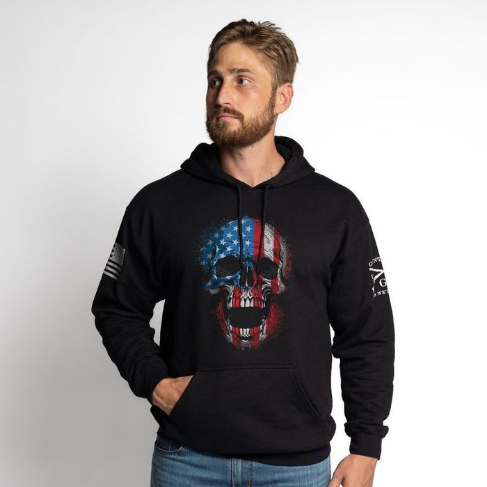 Man wearing a black hoodie with a skull and flag design on a white background