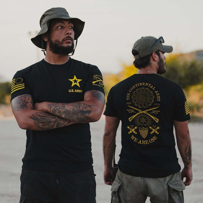 Two men wearing black t-shirts with military-themed designs outdoors.