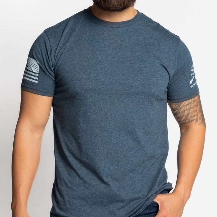 Man wearing a blue t-shirt with sleeve logos on a light gray background