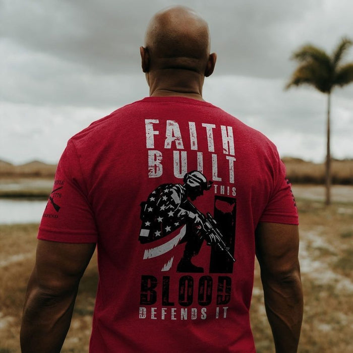 Man wearing a red t-shirt with a graphic and text, standing outdoors.