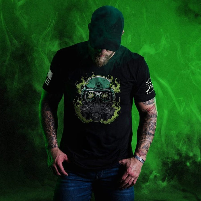 Person wearing a black t-shirt with a gas mask design against a green background