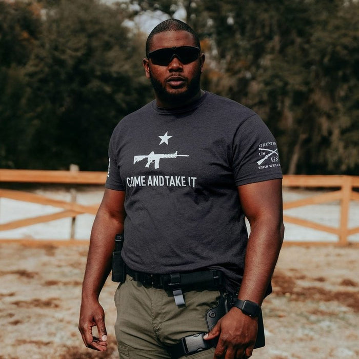 Man wearing a black t-shirt with a graphic and text, standing outdoors.