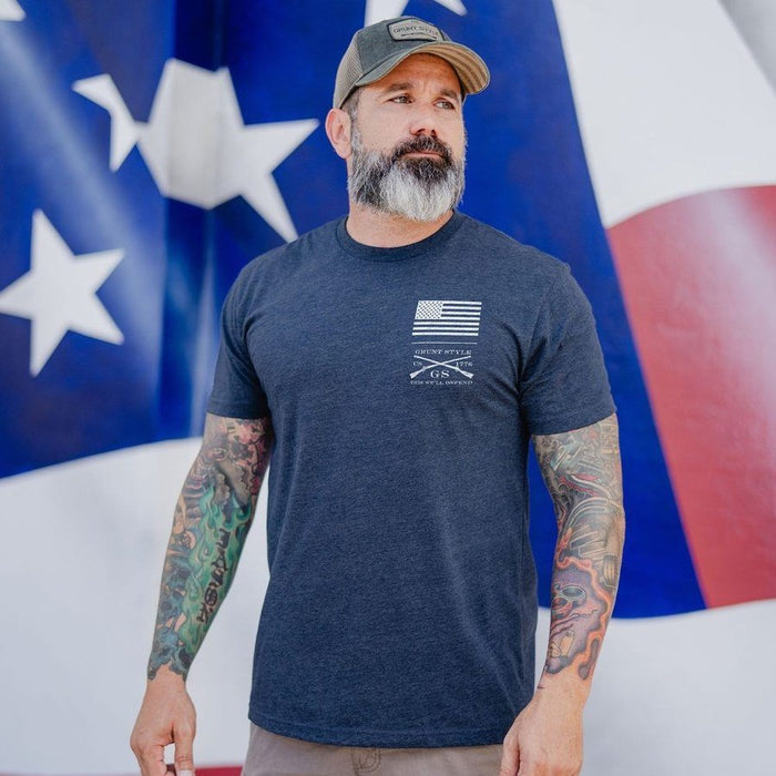 Man wearing a navy t-shirt with a logo in front of an American flag