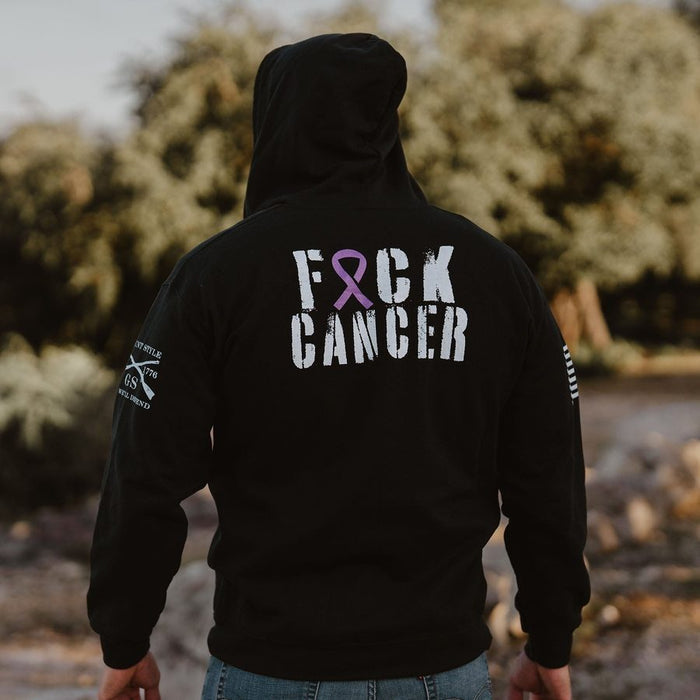 Person wearing a black hoodie with 'F*CK CANCER' text and pink ribbon on the back, standing outdoors.
