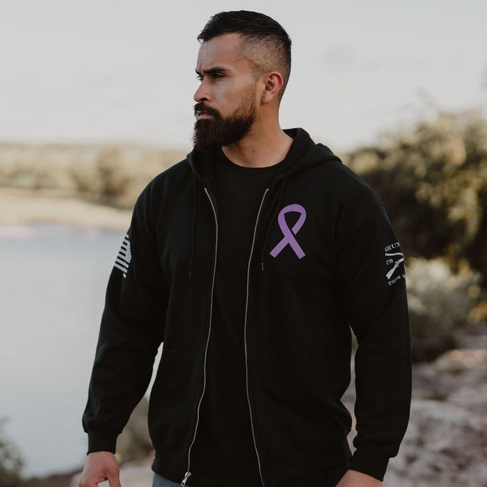 Man wearing a black hoodie with a purple ribbon on a blurred natural background