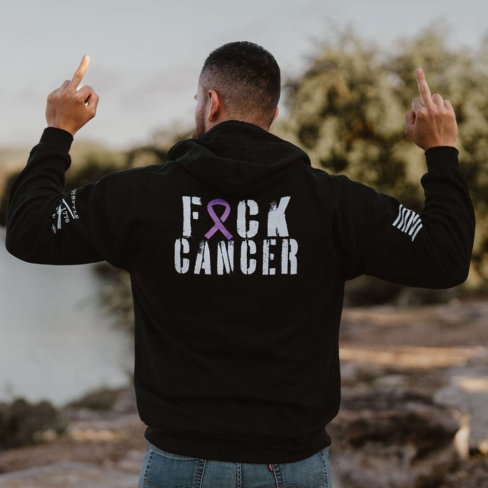 Person wearing a black hoodie with 'F*ck Cancer' and a pink ribbon on the back, standing outdoors.