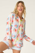 A woman wears the P.J. Salvage Frutta Fresca Summer Harvest Long Sleeve Button Up Top, a silky rayon sateen pajama shirt with a multicolor fruit print, posing against a plain light background.