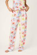 A person stands barefoot in P.J. Salvage Frutta Fresca Summer Harvest Open Leg Pants, featuring a relaxed fit, silky rayon sateen fabric, drawstring waist, and a playful fruit-and-vegetable print. The person’s face is not visible.