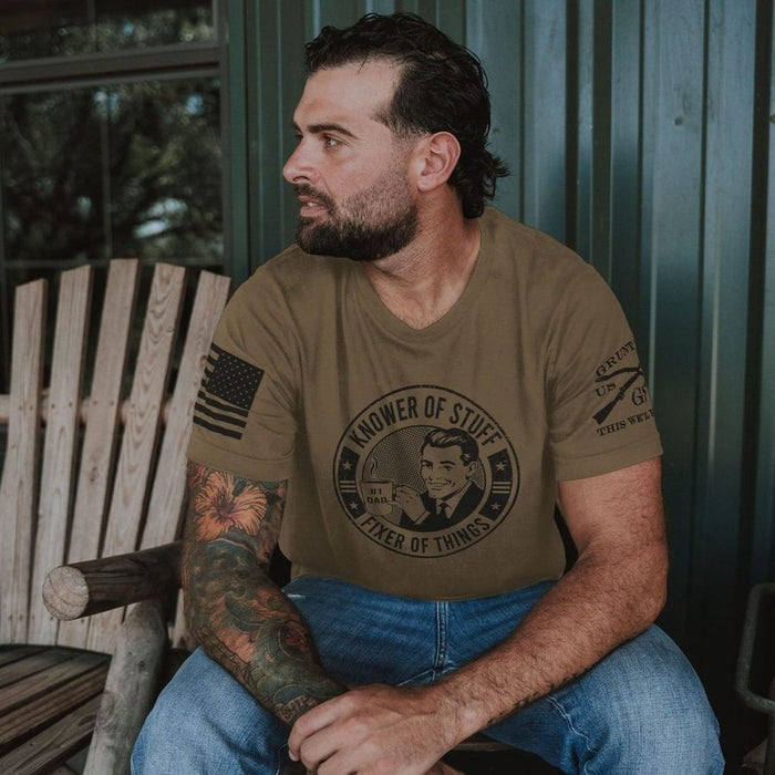 Man sitting on a wooden bench wearing a green t-shirt with a graphic design.