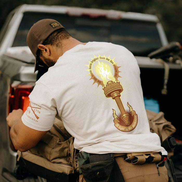 Man wearing a white t-shirt with a graphic design, standing next to a truck.