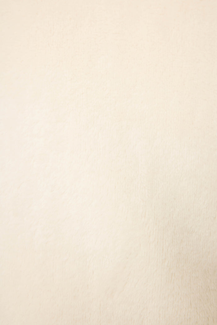 A close-up of the P.J. Salvage Luxe Plush Solid Ivory Robe reveals a smooth, light beige surface with a soft, fuzzy texture and even color, showcasing the robe's luxurious feel without visible patterns or prominent details.