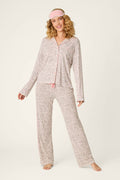 A smiling woman with curly blonde hair models the Modal Dreams Leopard Print 3-Piece PJ Set by P.J. Salvage, featuring a matching sleep mask and standing barefoot against a plain background.