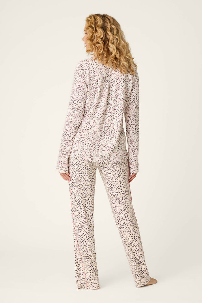 A woman with curly blonde hair stands barefoot, facing away from the camera, wearing the P.J. Salvage Modal Dreams Leopard Print 3-Piece PJ Set featuring a light background with a subtle dark leopard pattern.