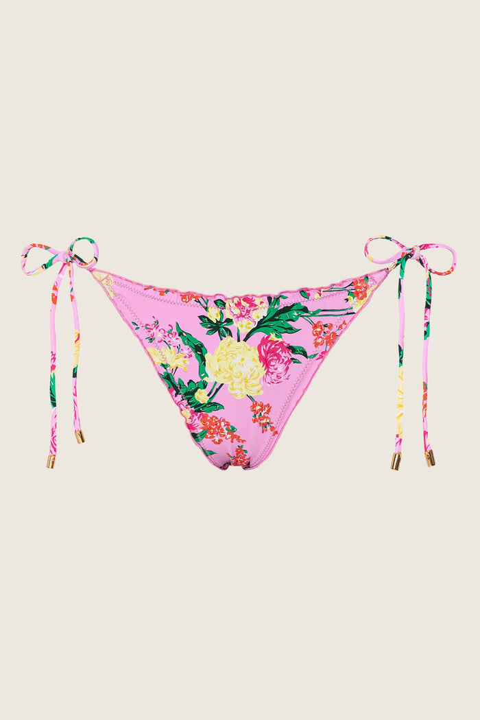 The PQ Swim PJS x PQ Swim Dahlia Embroidered Lettuce Edge Tie Side Bottom features a pink floral print with colorful flowers, green leaves, side ties with gold tips, and a lettuce edge, shown against a light background.