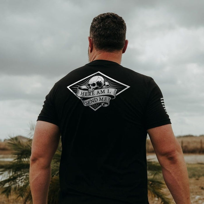 Man wearing a black t-shirt with a graphic design on the back, standing outdoors under a cloudy sky.