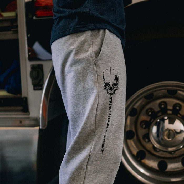 Person wearing gray sweatpants with a skull design and text in a garage setting
