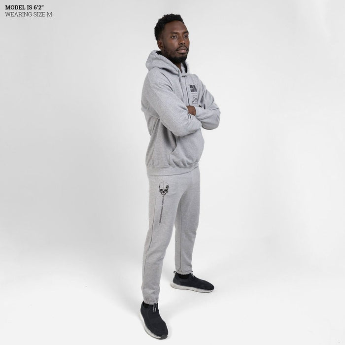 Man wearing a gray tracksuit with a logo on a white background