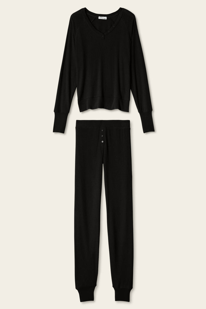 The P.J. Salvage Textured Essentials Black Lounge Set features a matching ensemble of soft, ribbed fabric, including a relaxed V-neck long-sleeve top and button-fly pants, displayed on a plain light background.