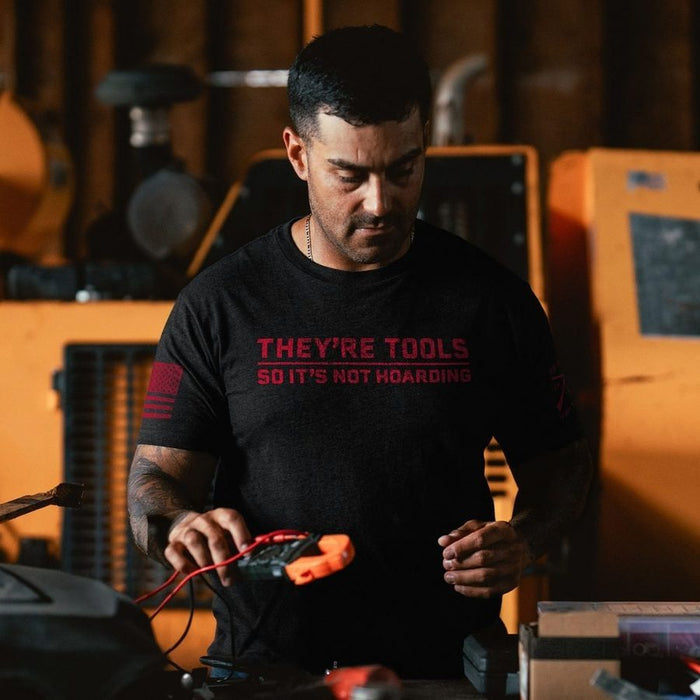 Man wearing a black t-shirt with red text in a workshop setting