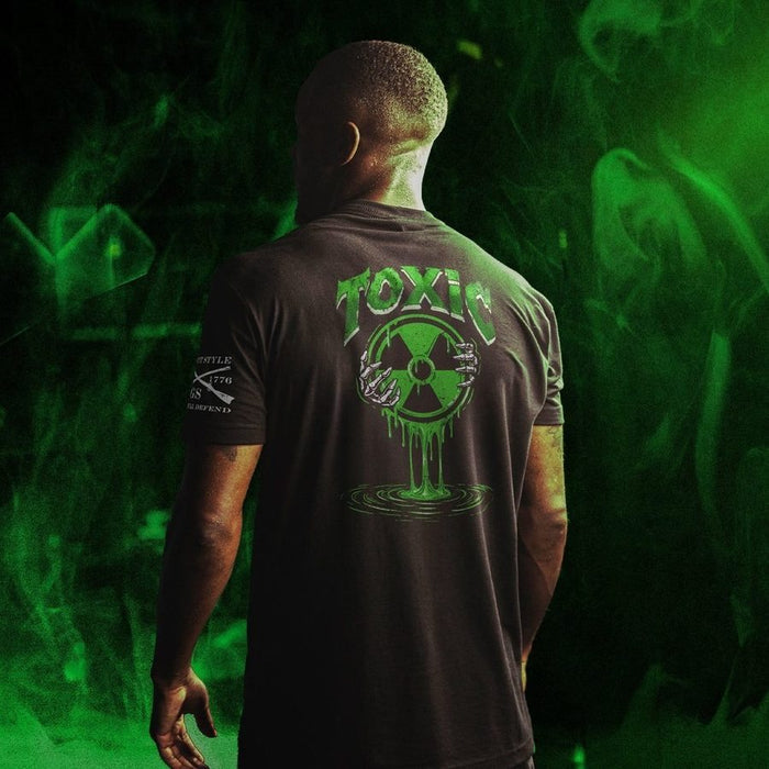 Person wearing a black t-shirt with a green 'TOXIC' design on the back, against a green smoke background.