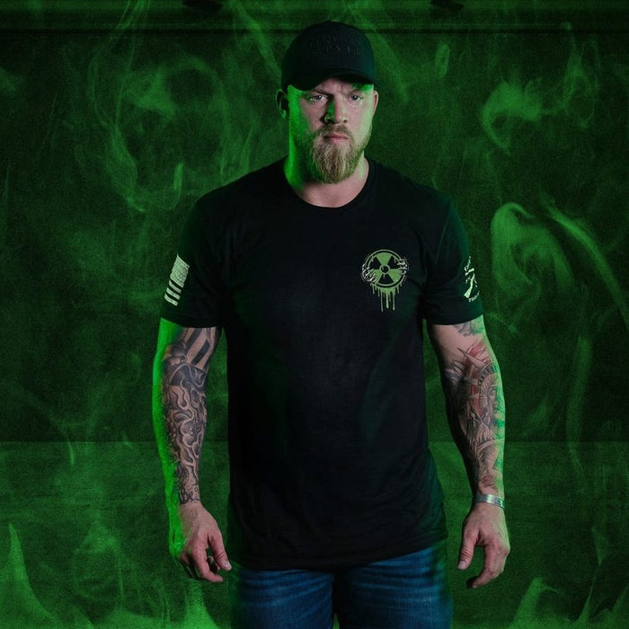 Man wearing a black t-shirt with a logo on a green smoke background