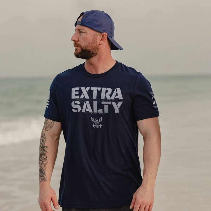 Man wearing a navy blue t-shirt with 'Extra Salty' text on a beach