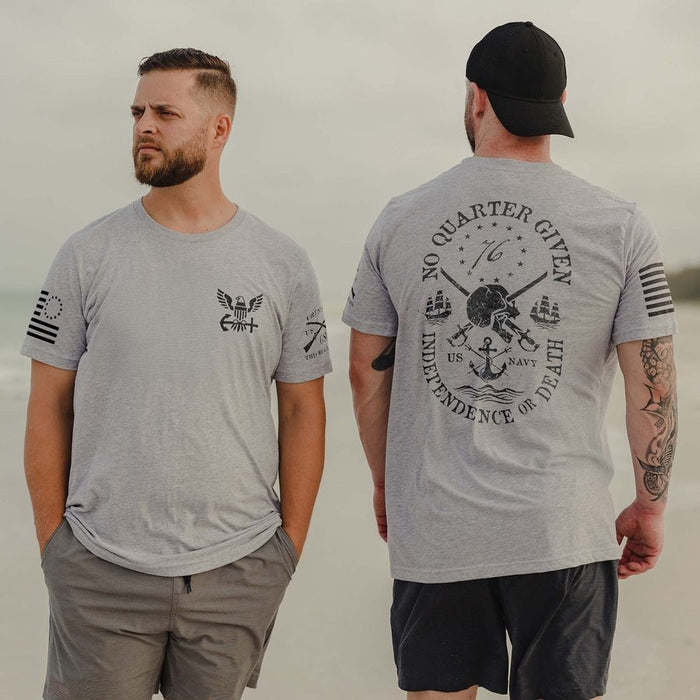 Man wearing a gray t-shirt with military-themed designs on a beach.