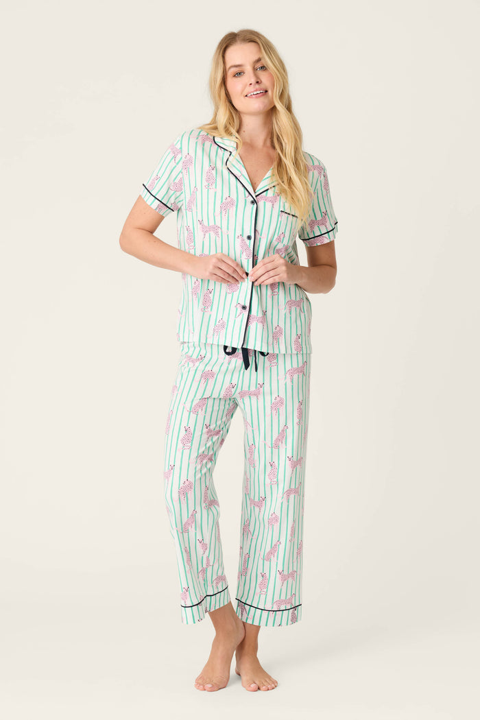 A person stands barefoot against a plain background, wearing the Whimsy Cool Cat Cropped PJ Set by P.J. Salvage—a matching pajama set featuring short sleeves and buttons on the top, and ankle-length pants with a playful cat print.