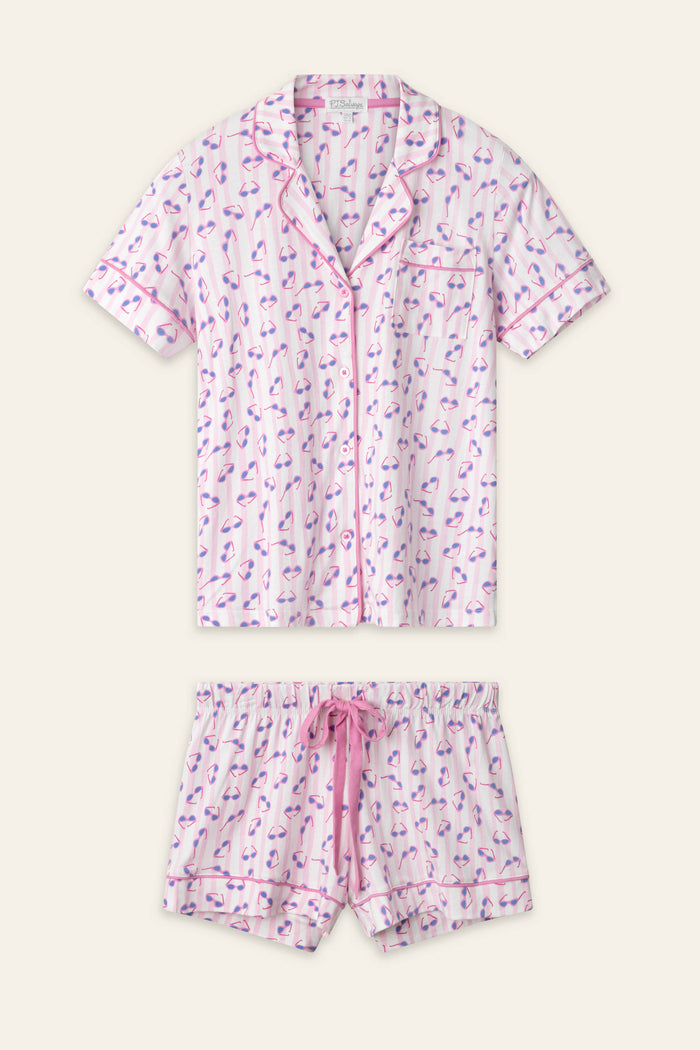The Whimsy Retro Shades Short PJ Set by P.J. Salvage includes a short-sleeve button-up top and drawstring shorts with a pink and purple flamingo print on white, finished with pink trim.
