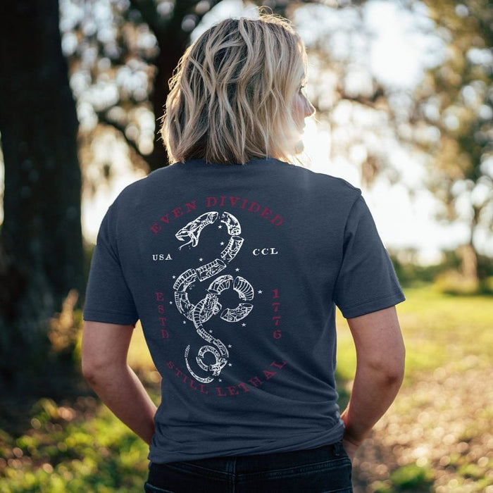 Person wearing a dark blue t-shirt with a snake design and text outdoors.