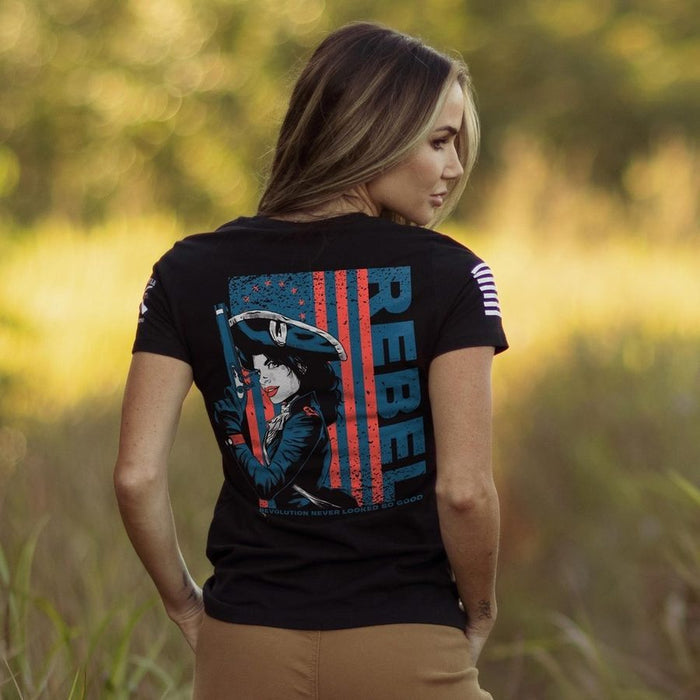 Woman wearing a black t-shirt with a graphic design and the word 'REBEL' outdoors.