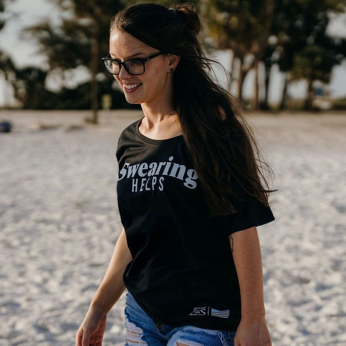 Woman wearing a black t-shirt with text on a sandy background